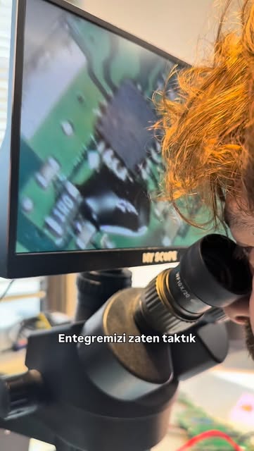 Teknisyen mikroskoptan bakarken ekranda anakart üzerindeki entegre büyütülmüş olarak görünüyor